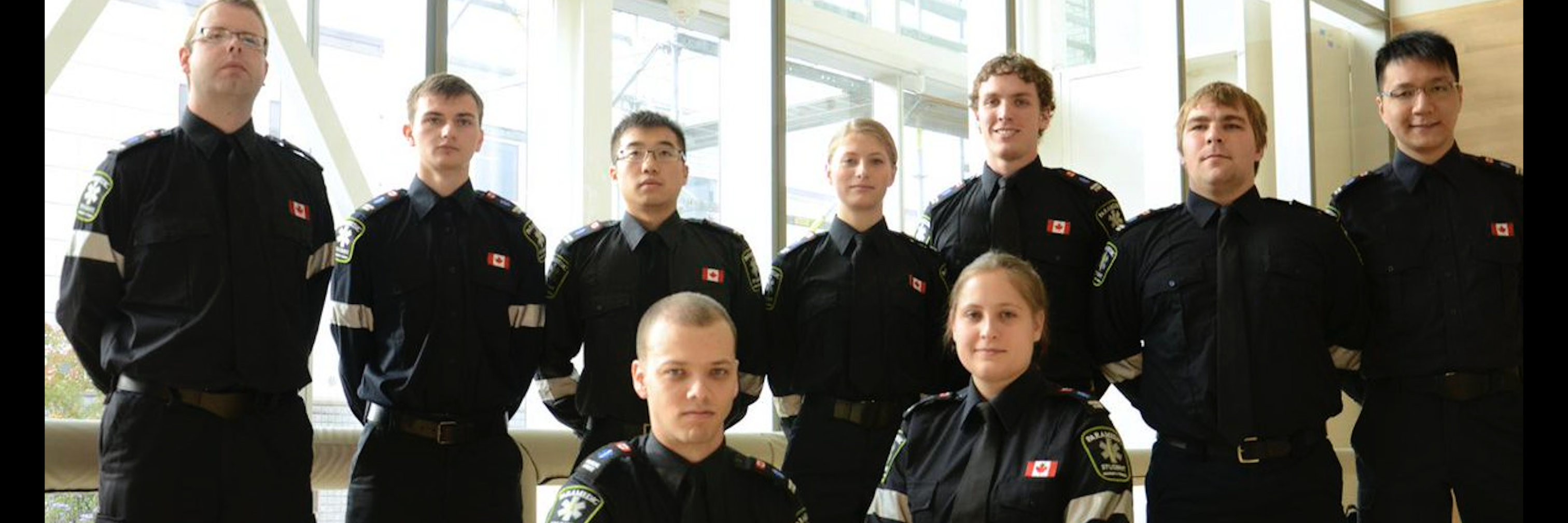 Paramedicine students posing in uniform against a window