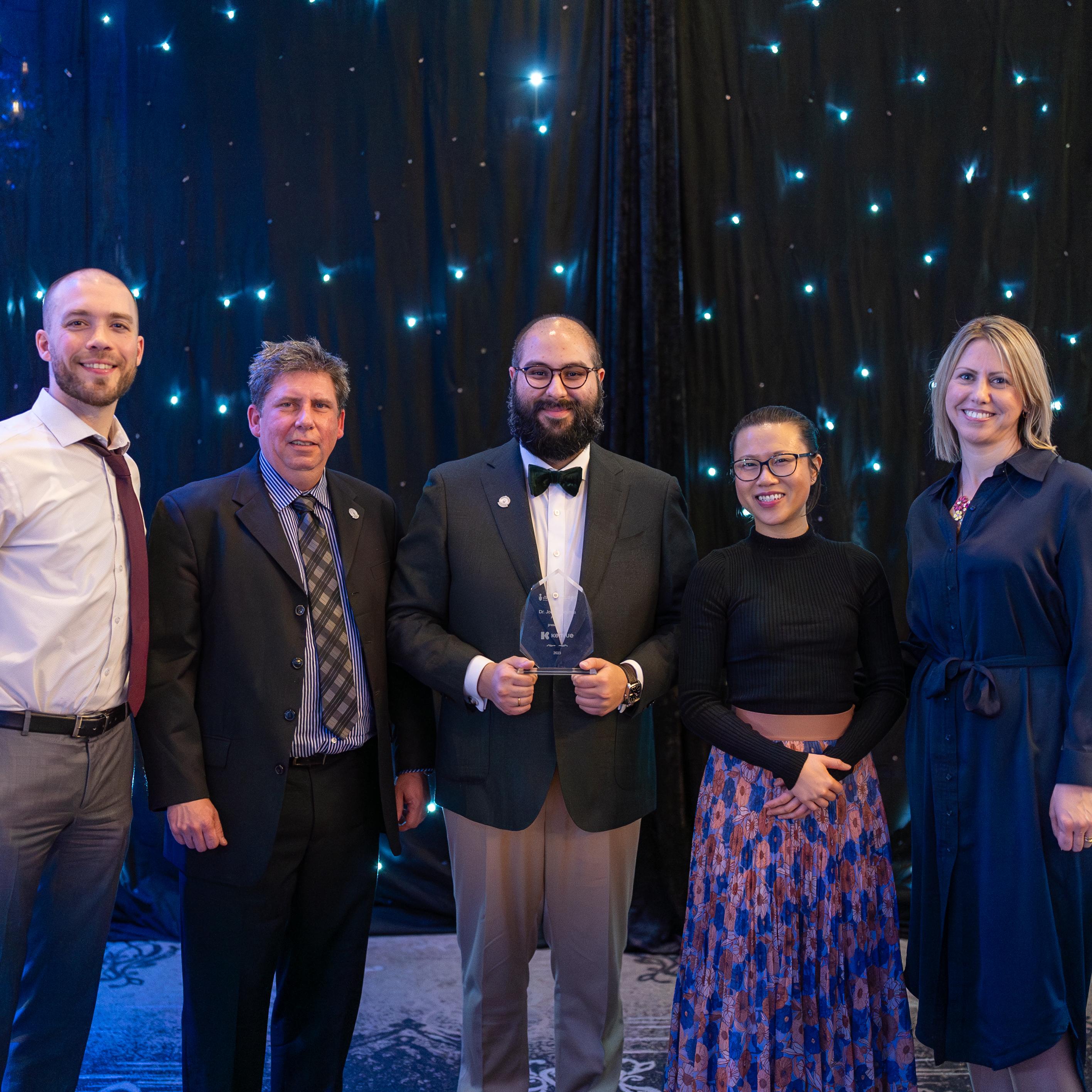 Kenvue team smiles while accepting the Dr. Jon Dellandrea Award in front of a starry background during the Management Gala on March 8.