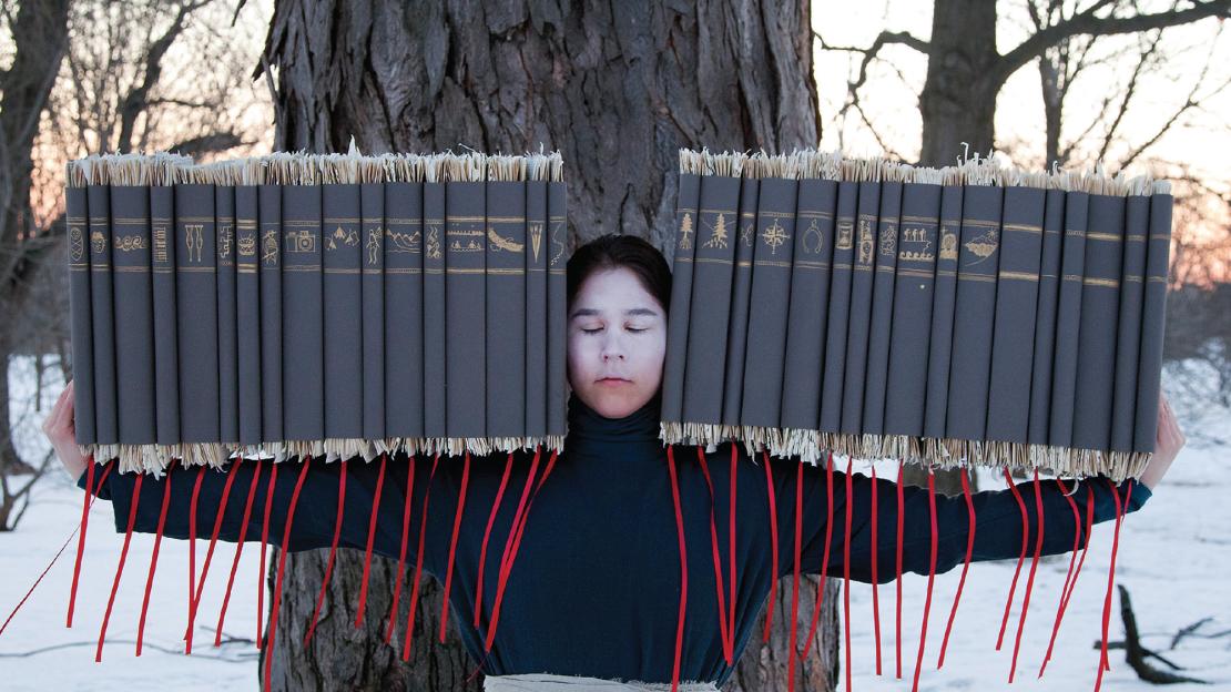 Indigenous teenager holding many books of law.