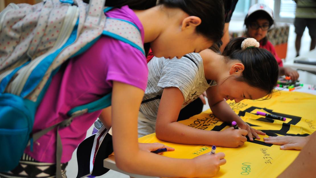 U of T Scarborough campers write out their well wishes on the Invictus Games flags. (Photo by Raquel A. Russell)