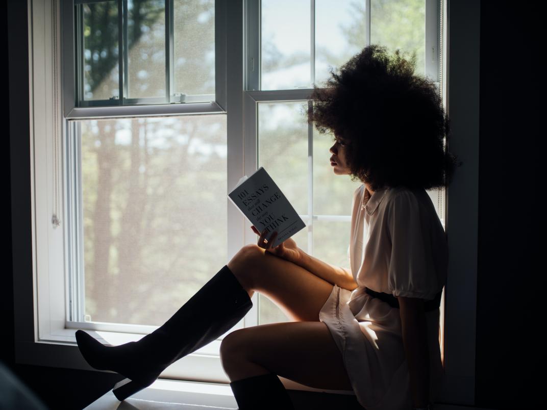 A person sitting by the window reading a book