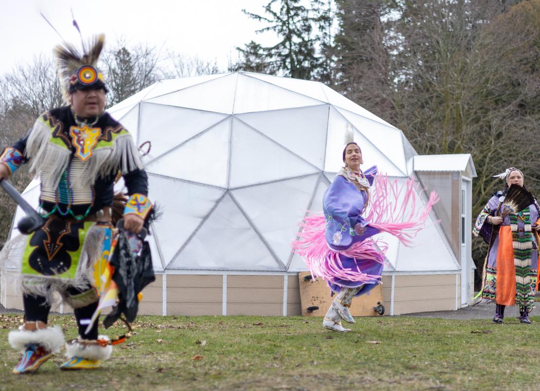 Three Indigenous dancers performing in front of the new grrenhouse domes