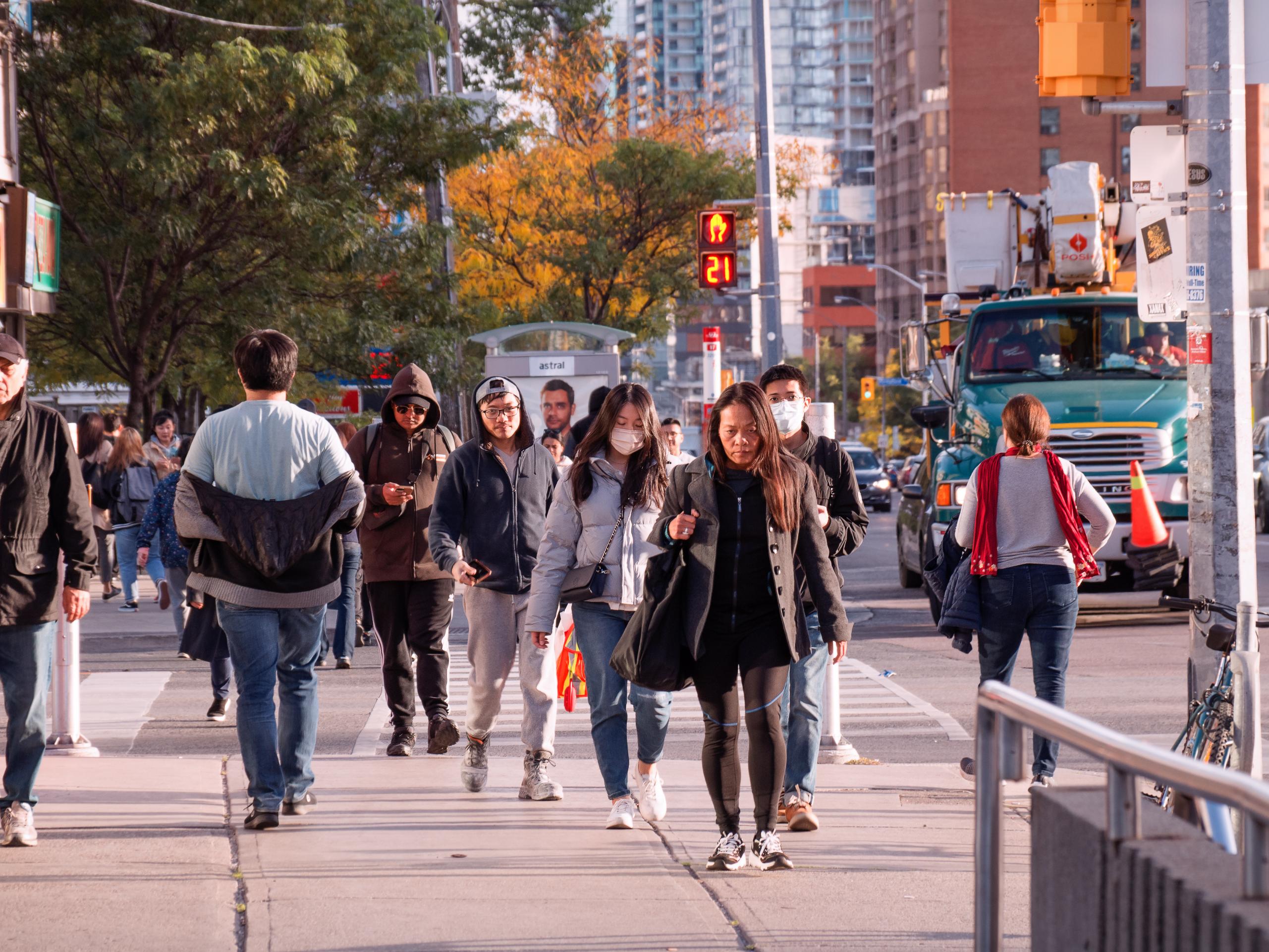 A crowd walks on a Toronto street, early evening, fall 2022