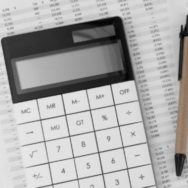 a calculator and a pen on top of a pile of balance sheet 
