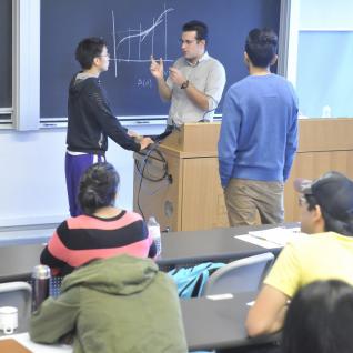 Professor and student engaged in conversation at front of classroom