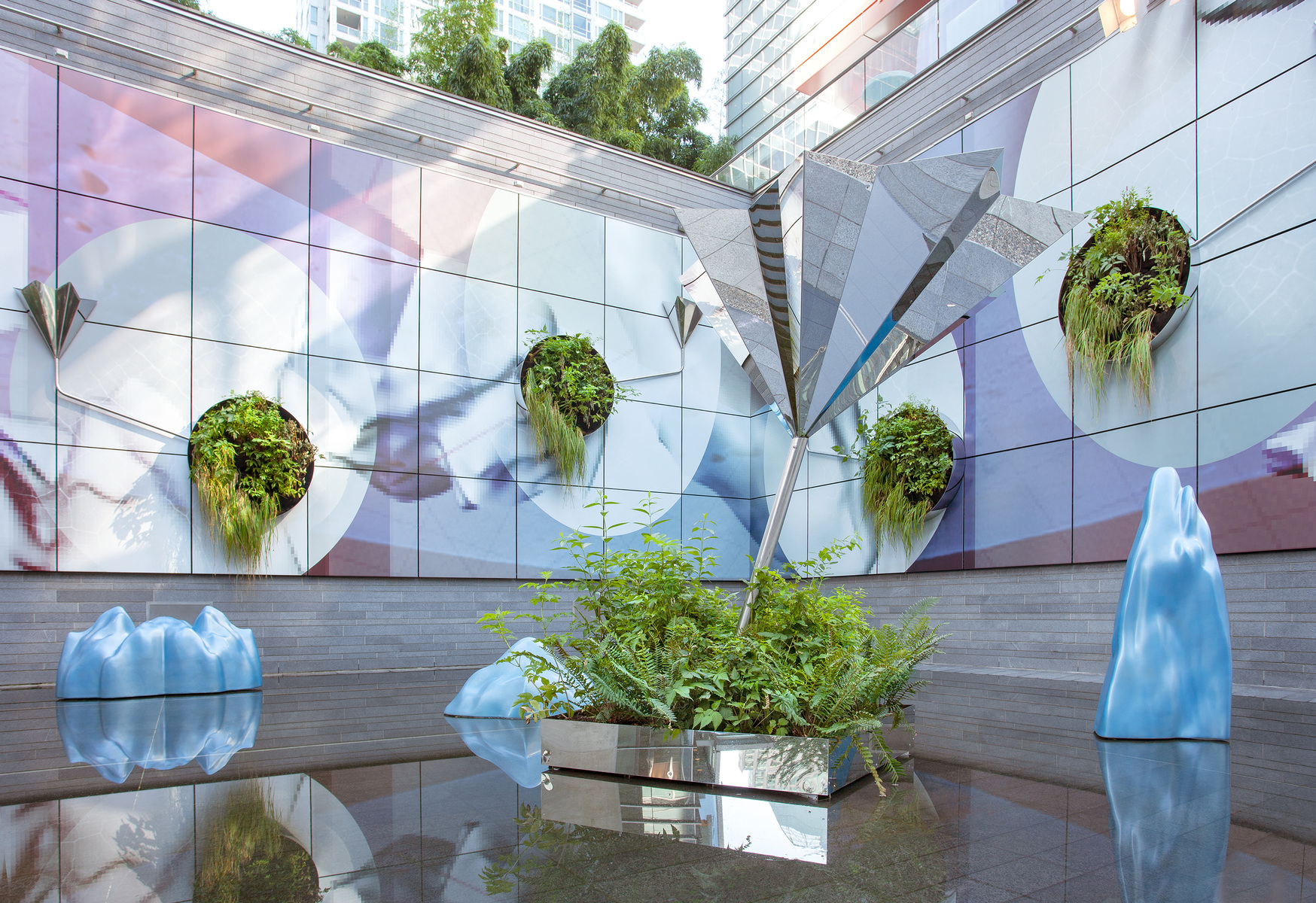 Installation view of "All That Melts",  reflective architectural vernacular with mirror-polished stainless steel planters, glossy reflecting pool where pearly-blue icebergs float in their own meltwater