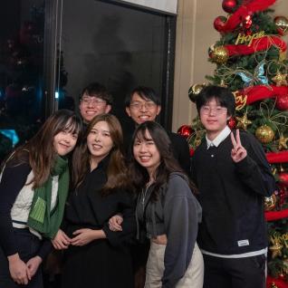 The group of students posing for a photo in front of a christmas tree