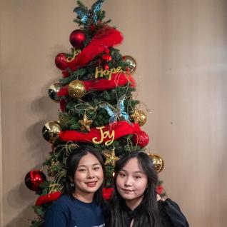 ACM engage volunteer and her friend posing in front of a christmas tree