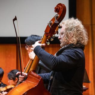 A bass violin performer playing in the String Orchestra ensemble