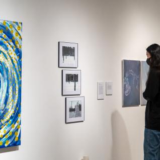 A student viewing artworks on the gallery wall.