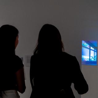 Two students viewing a projected artwork on the gallery wall.