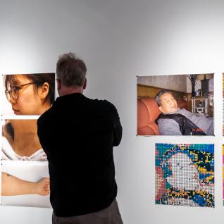 Studio Art Professor Arnold Koroshegyi viewing two student photography artworks.