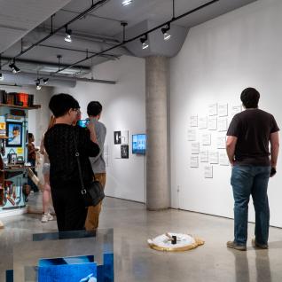 A wide shot of the east gallery space showing attendances viewing artworks around the gallery.