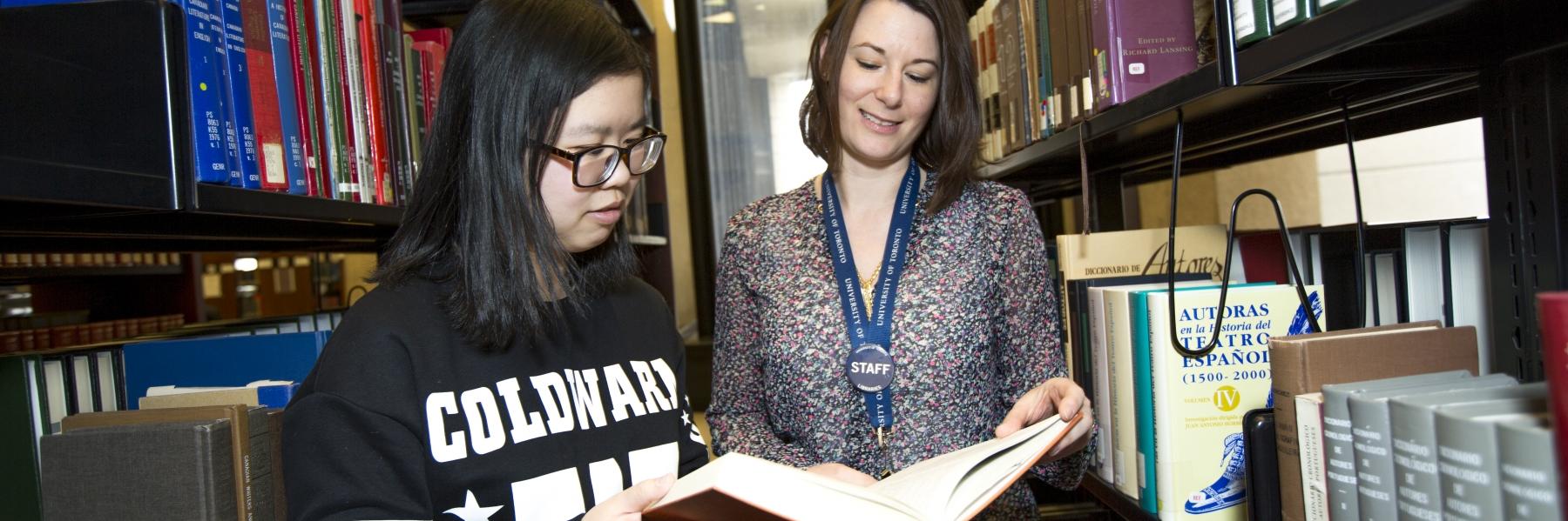 student in library with staff member