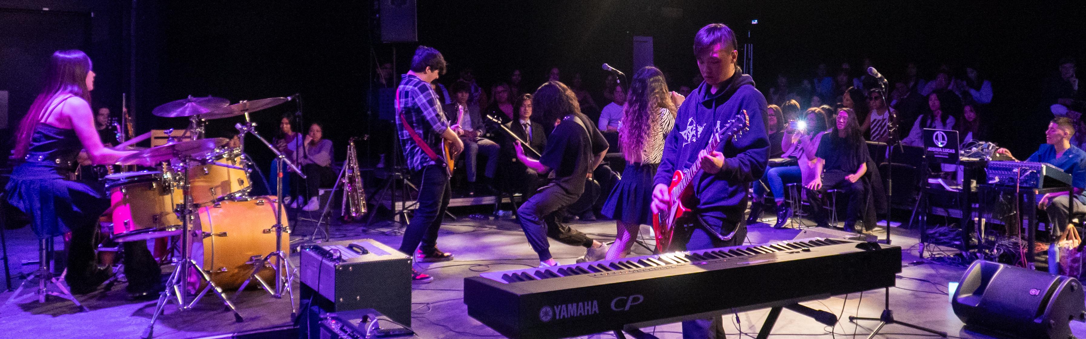 Students onstage at a concert, keyboard in the foreground