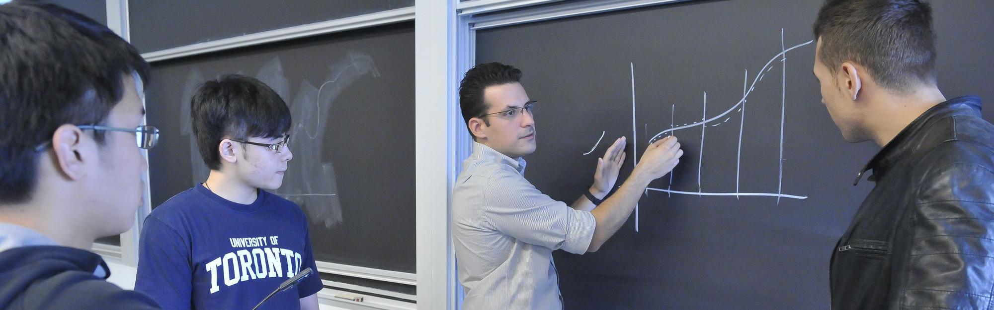 A professor showing a curve on a blackboard with three students looking on