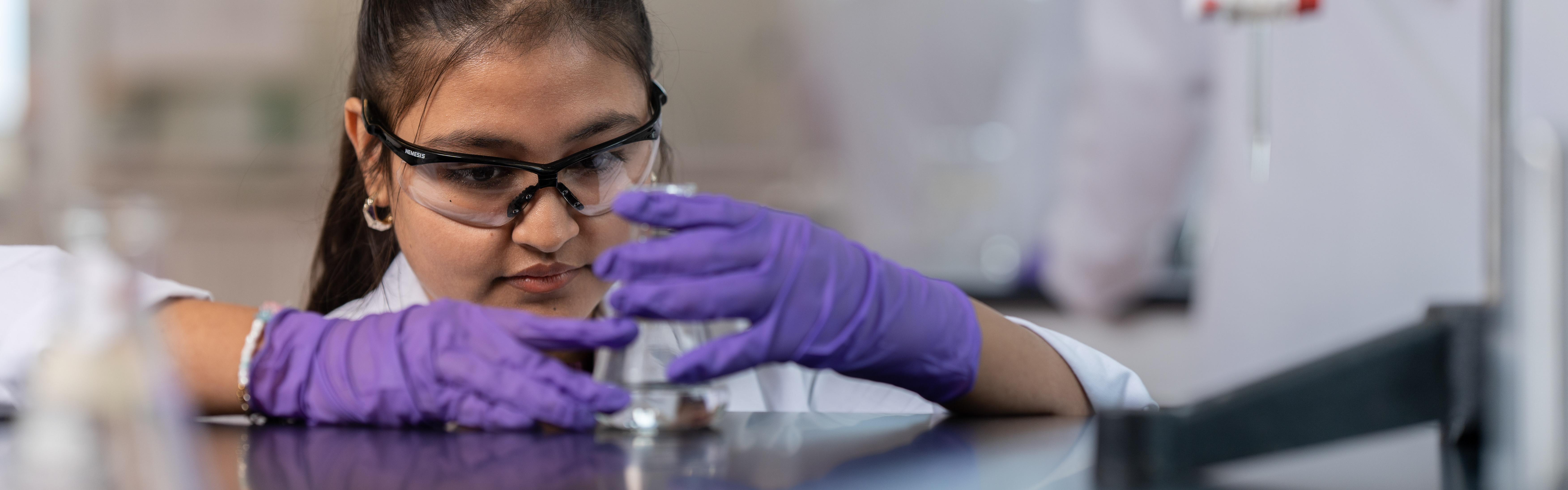 Student in a lab examining a beaker