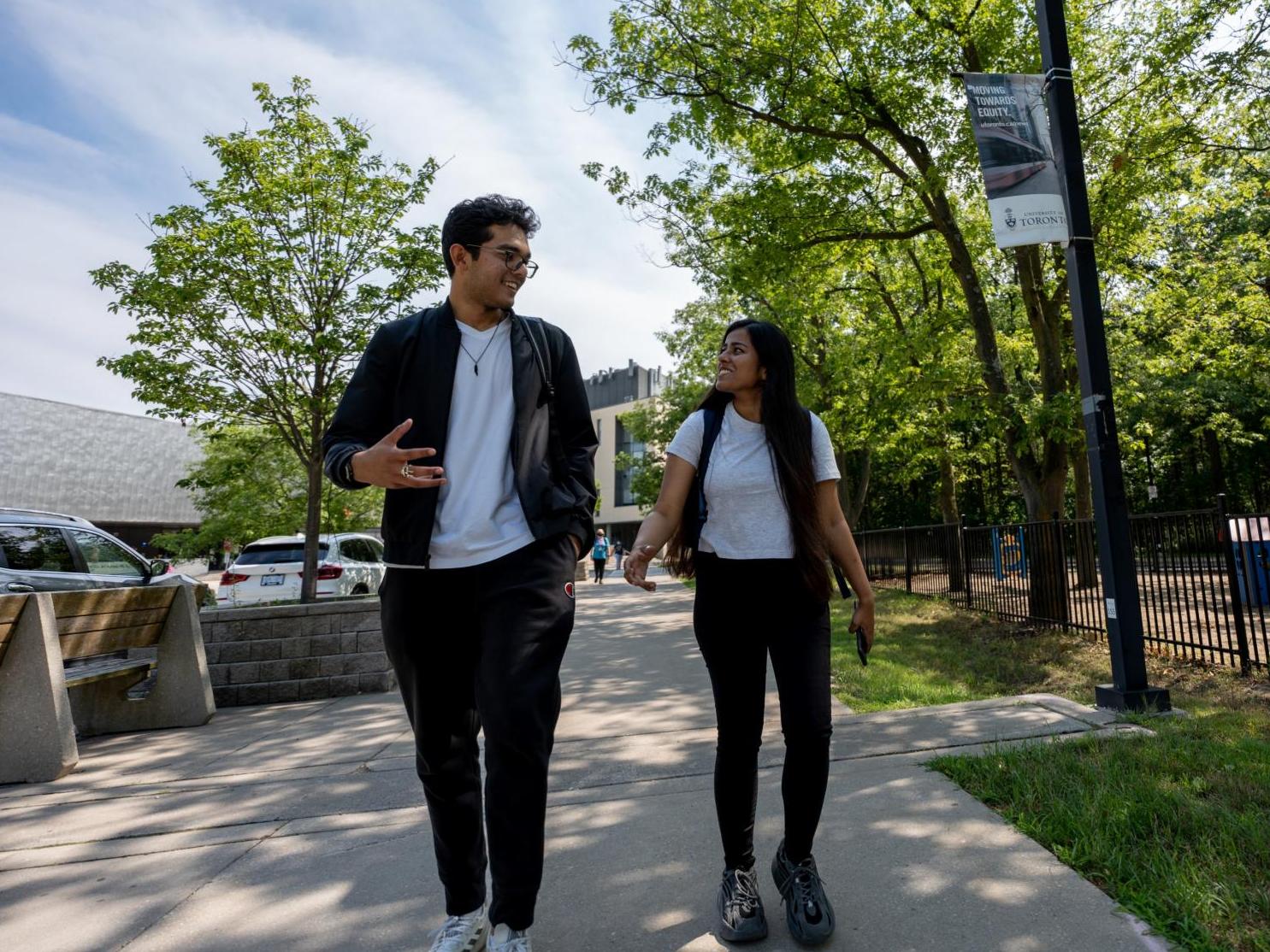Two students chatting while walking on campus