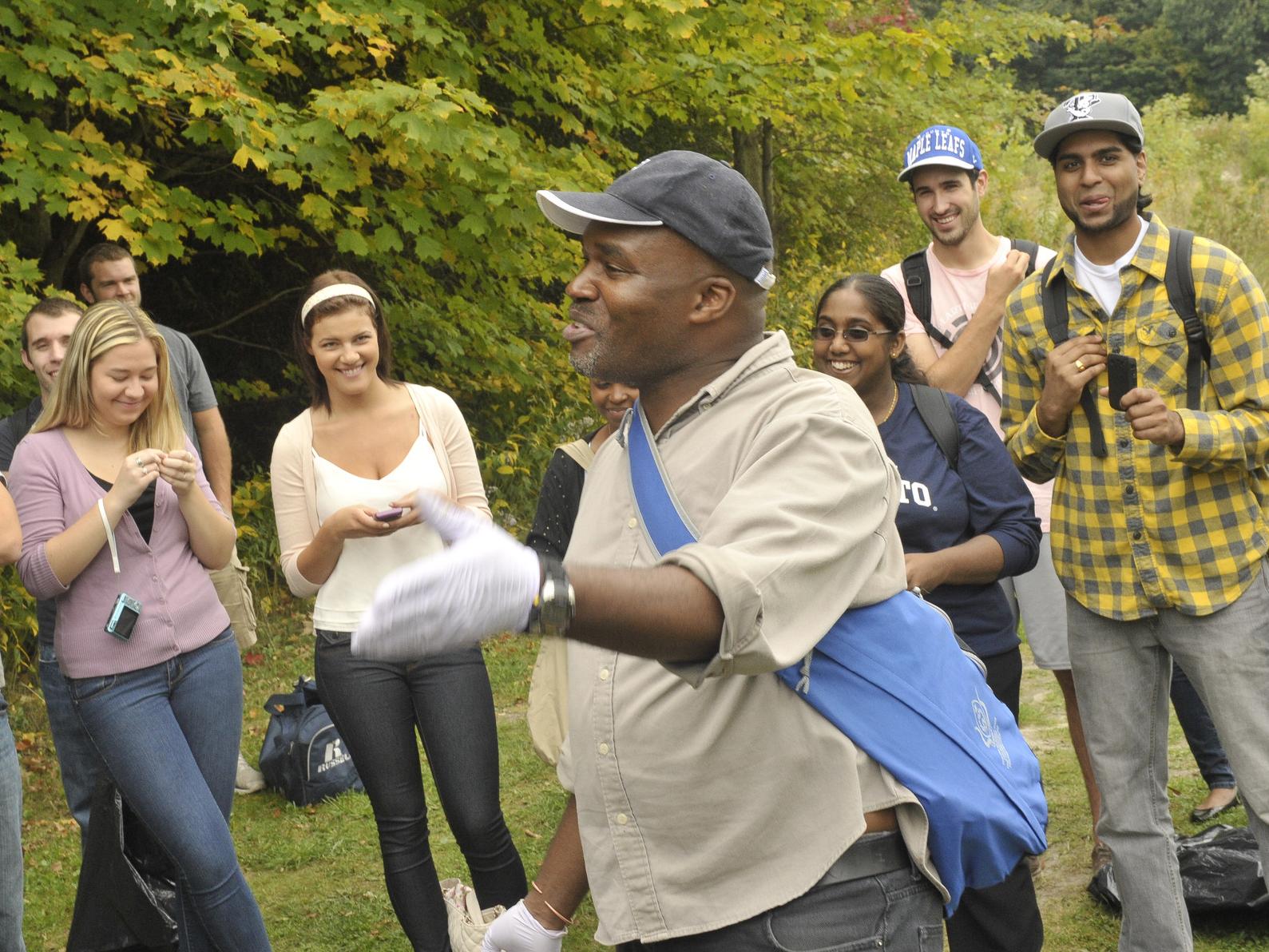 Professor Thembela Kepe with a group of students in a field setting with trees and grass
