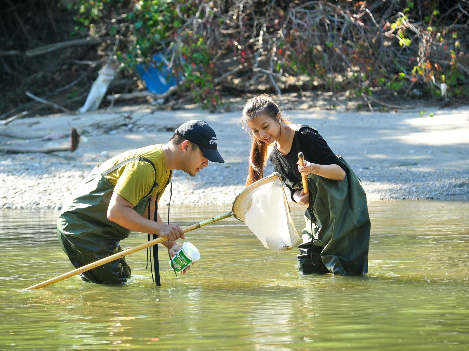 Two students in a creek with a net and a scoop