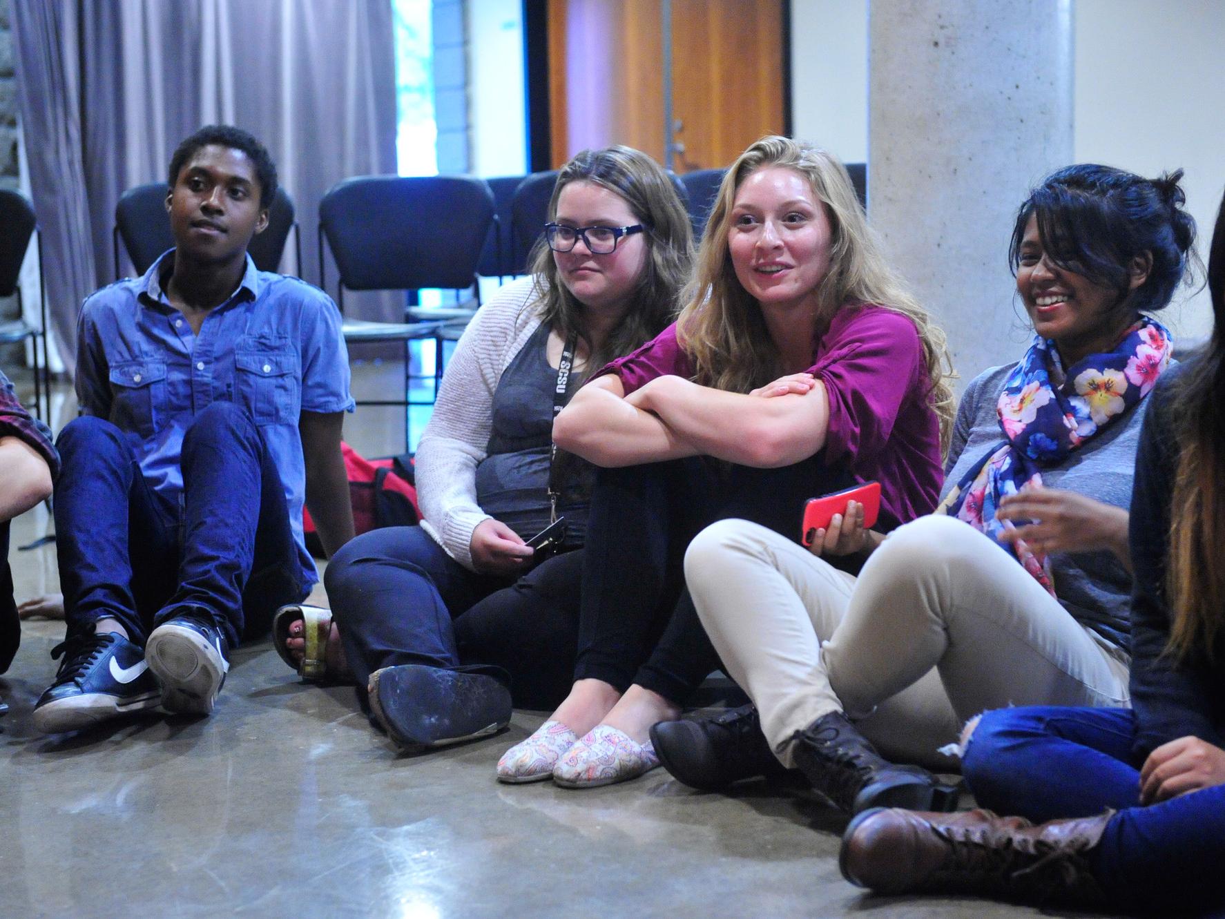A group of students sitting on the floor listening to each other