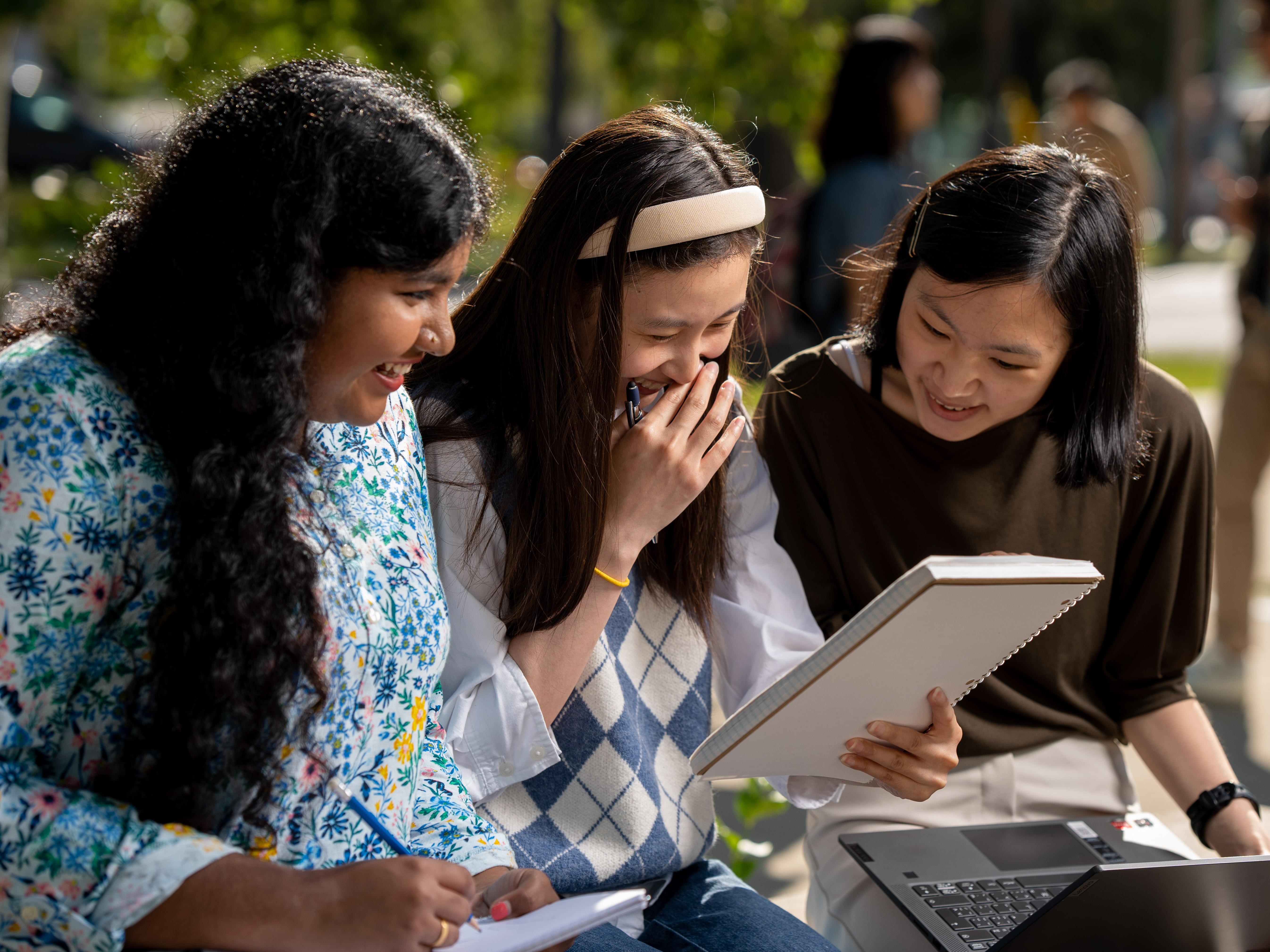 Students laughing over a notebook