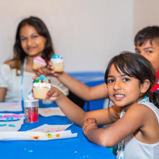 young children holding up their decorated cupcakes