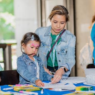 a mother helps her young daughetr with fingerpainting