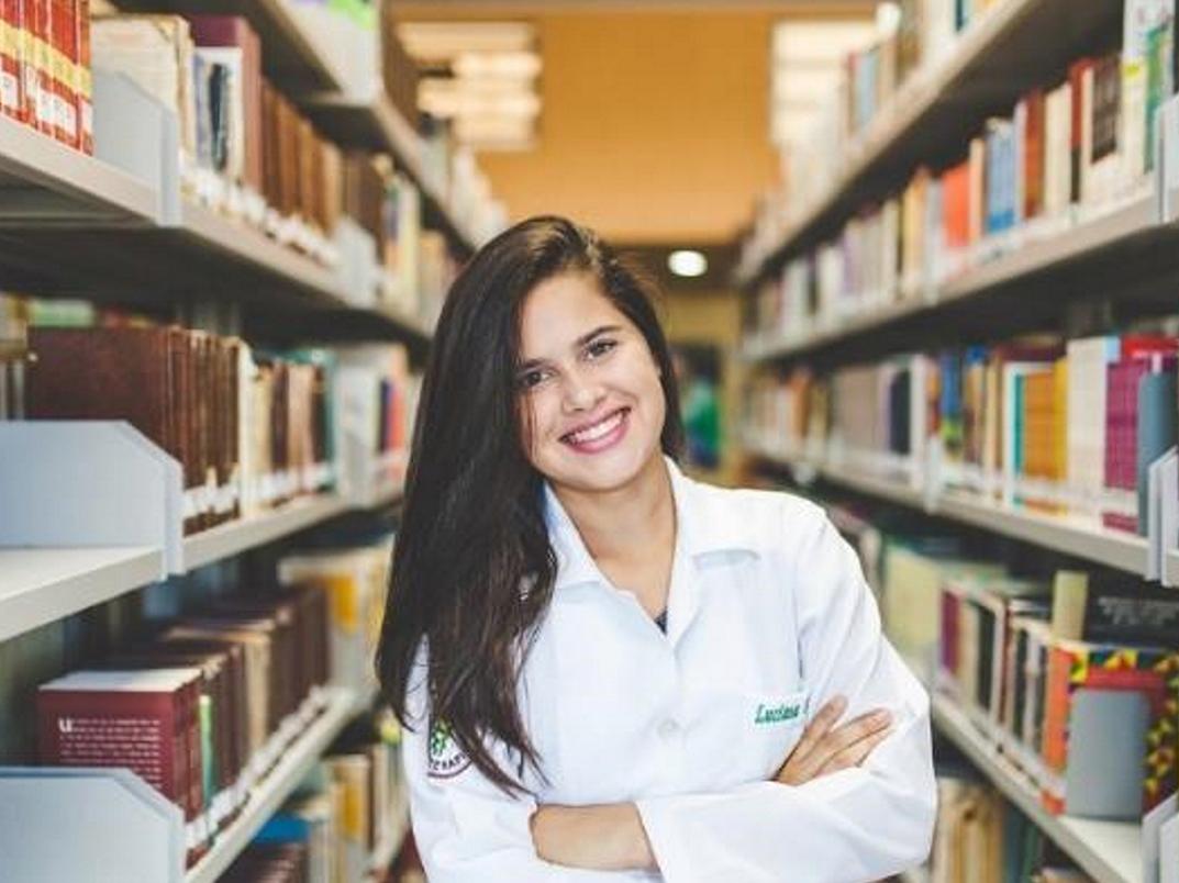 Smiling girl standing in library with arms folded