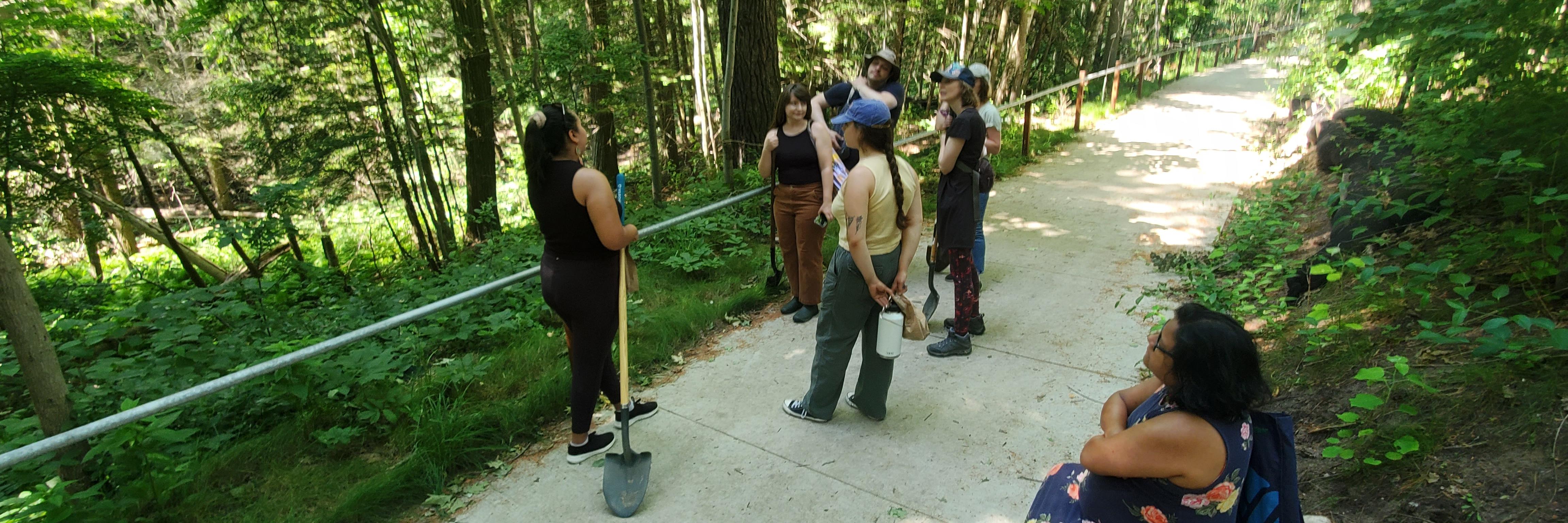 People standing around forest with shovels 