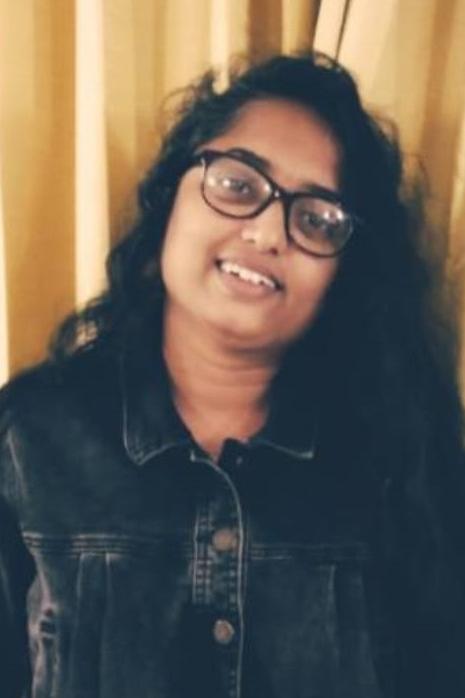 Photo of Shanmu wearing dark plastic rimmed glasses and a dark denim jacket
