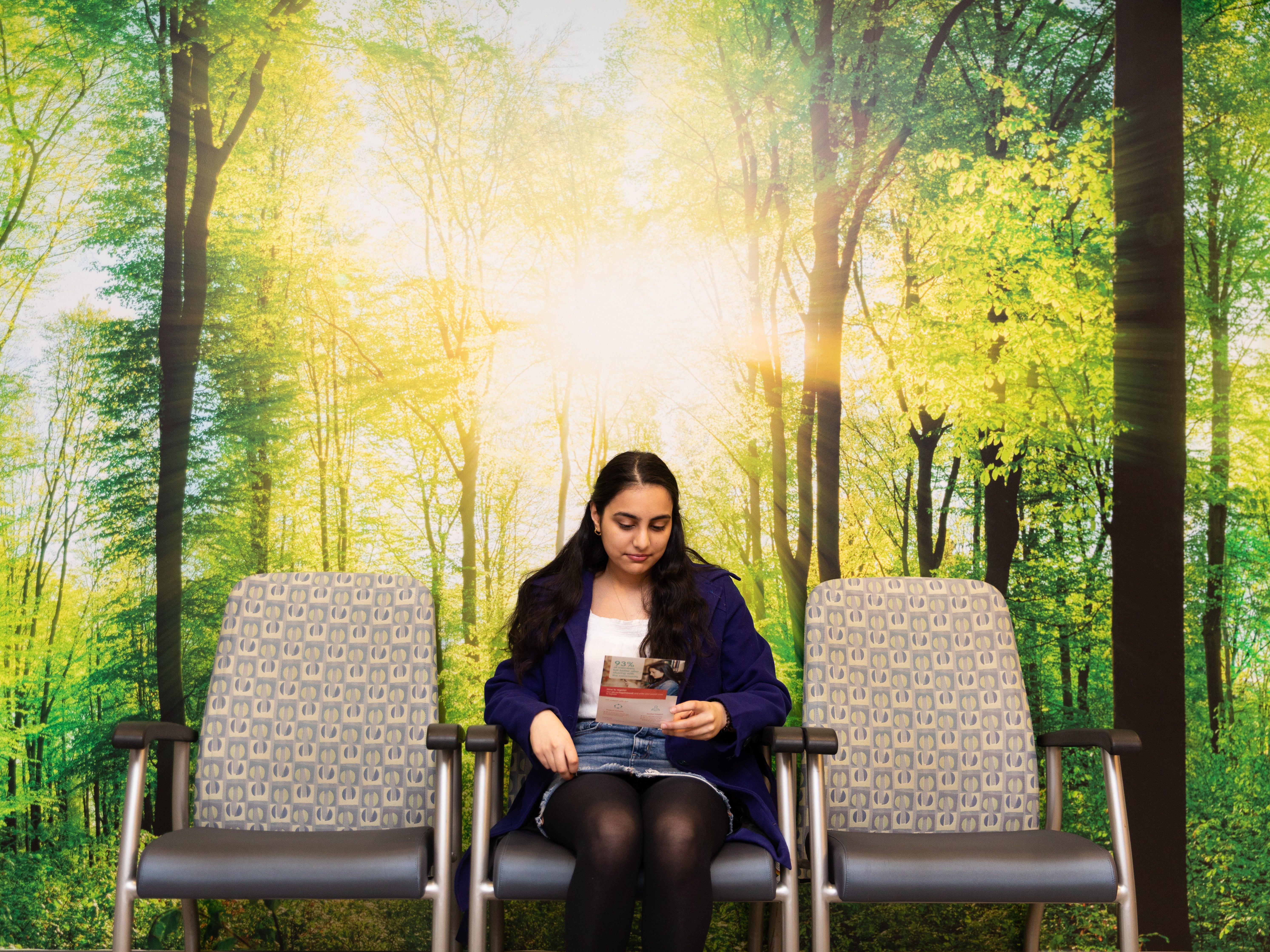Student in waiting room with image of trees behind. 