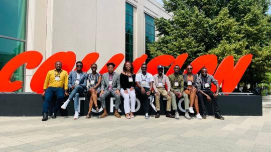 A group of startup founders visiting from African pose in front of a large red sign that reads "Collision" in cutout letters.