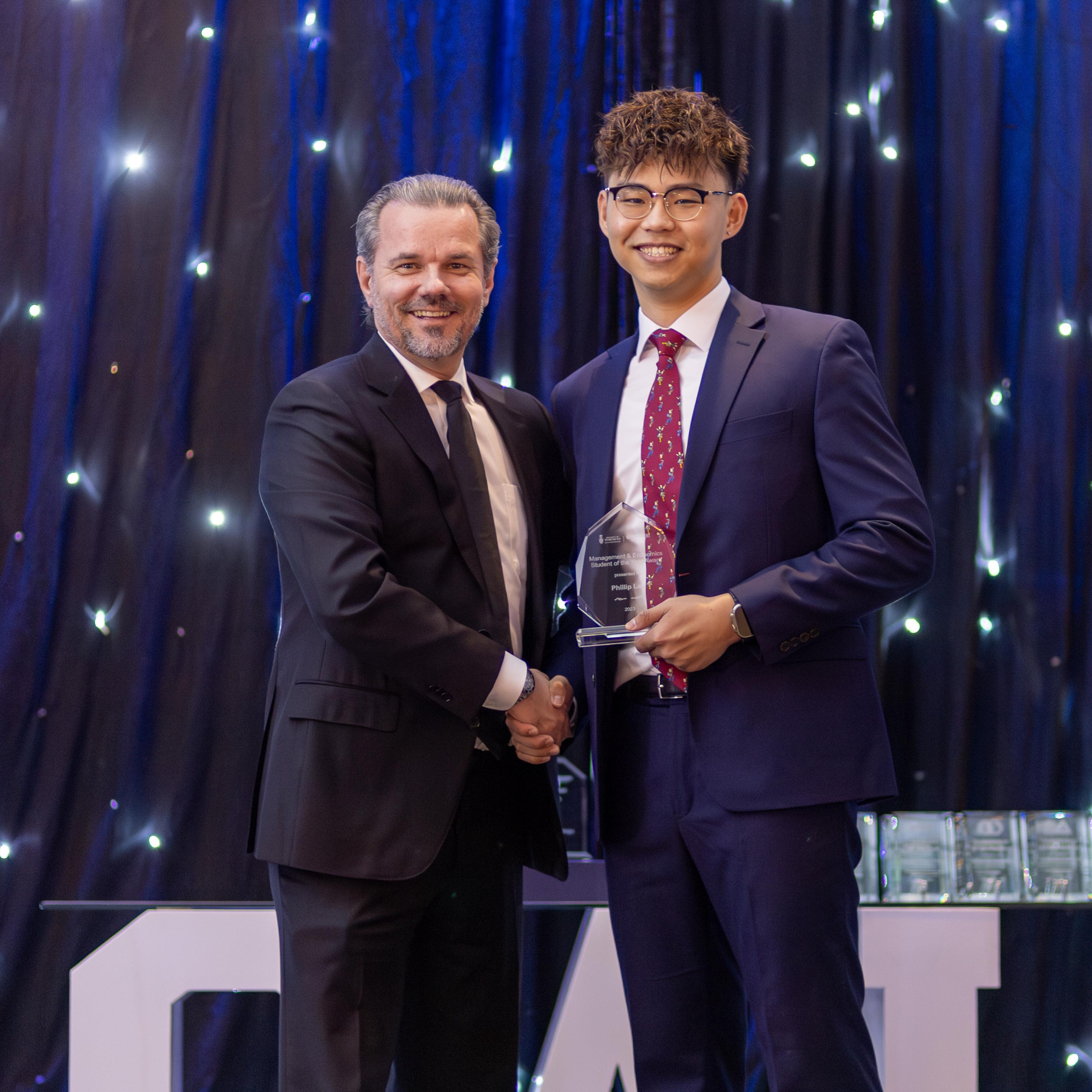 Phillip Lau smiles while shaking hands with the Acting Chair of Management Jean de Bettignies during the University of Toronto Scarborough Management Gala.