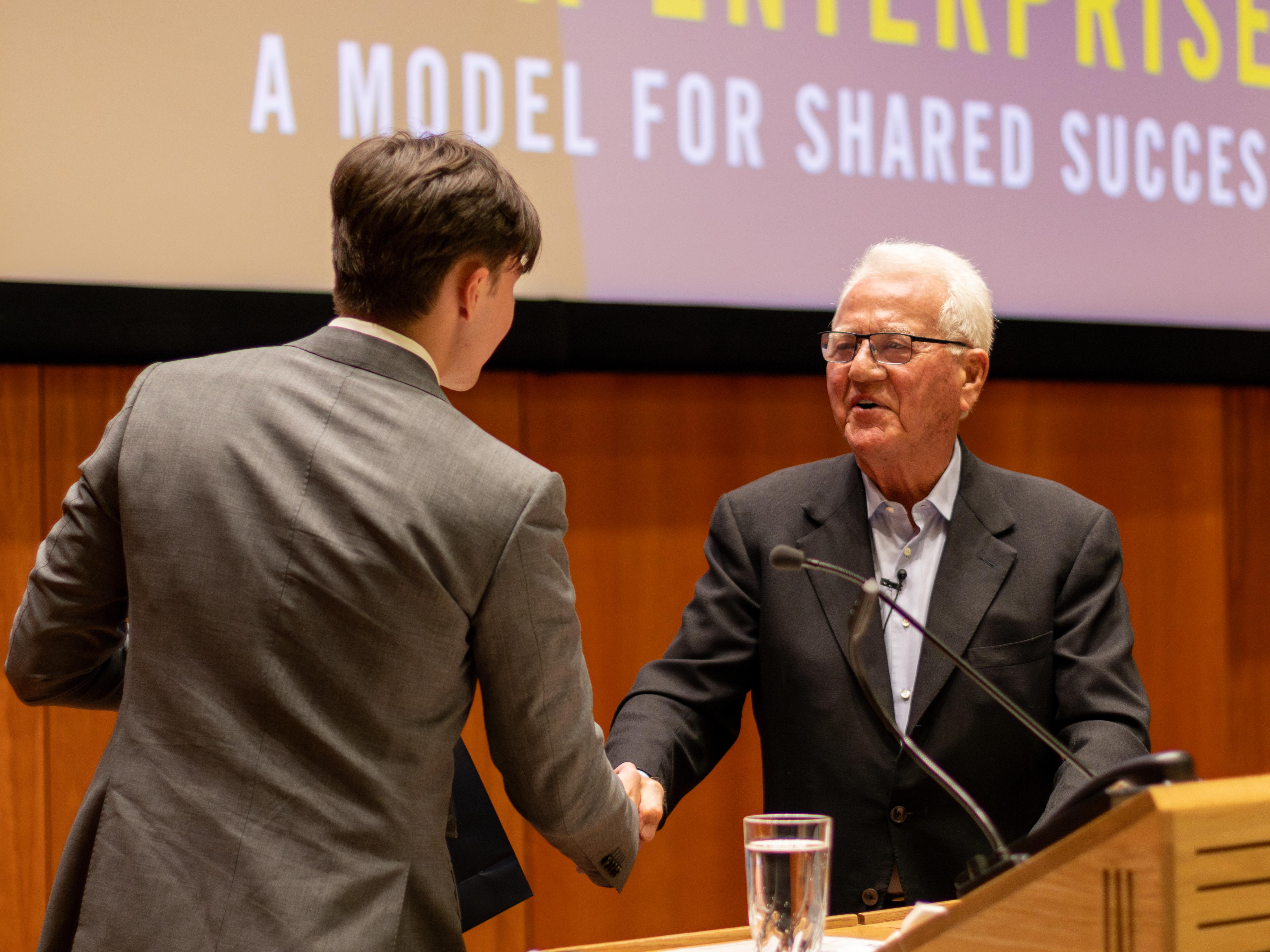 Frank Stronach shakes hands with Management student Spencer Chang