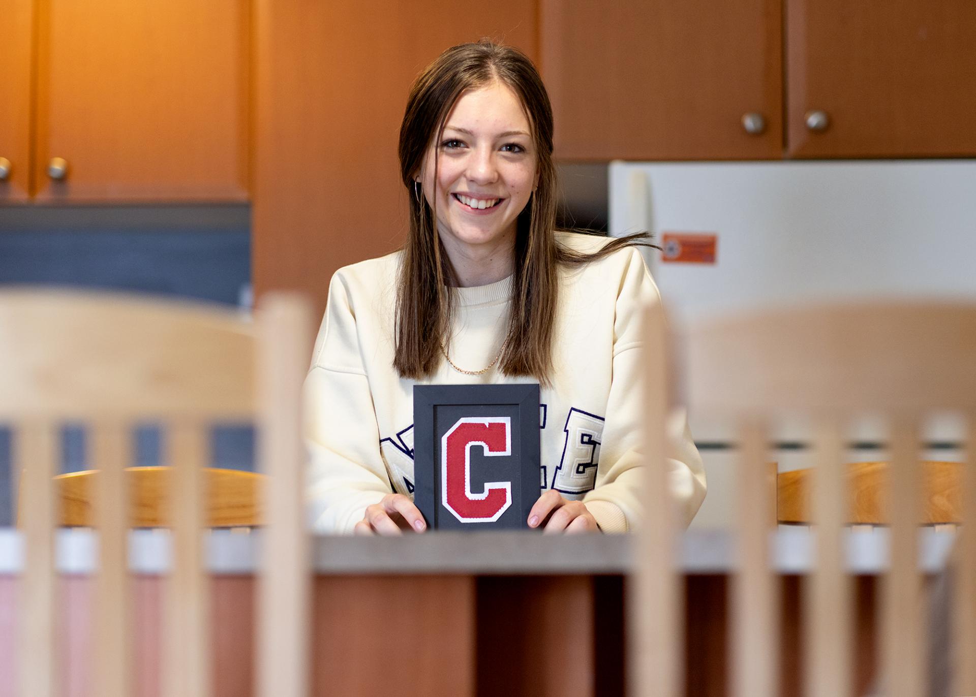 A photo of Erin Middleton with a framed C from a hockey jersey