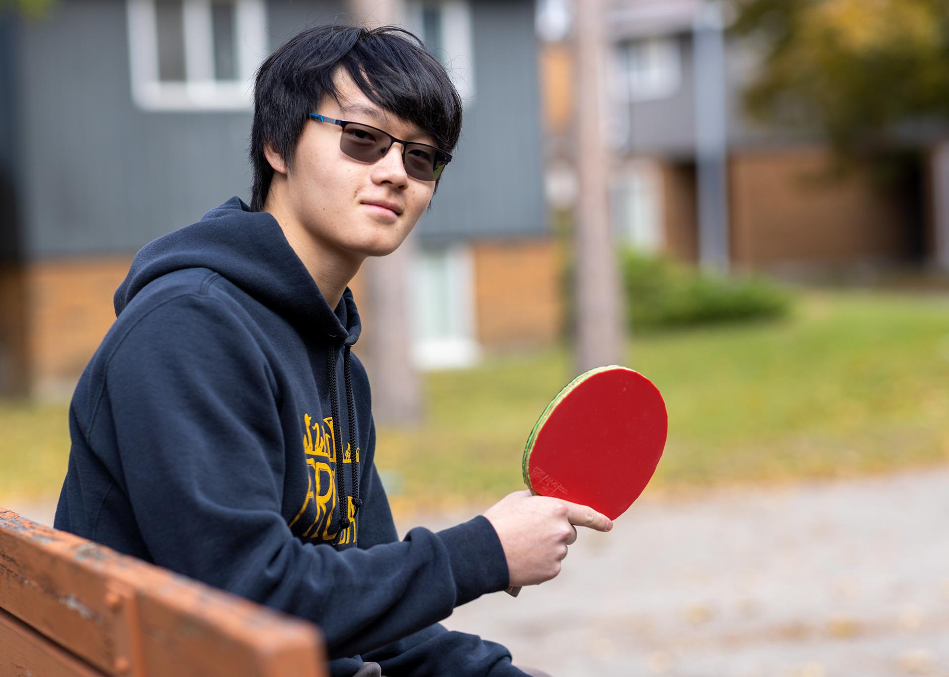 A photo of Julian Liu with a ping pong paddle