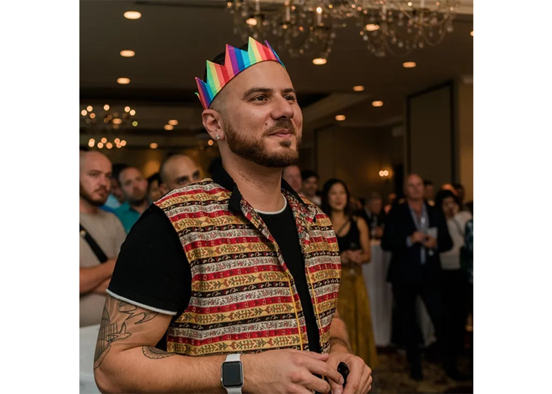 Danny Ramadan wearing a rainbow paper crown at an event