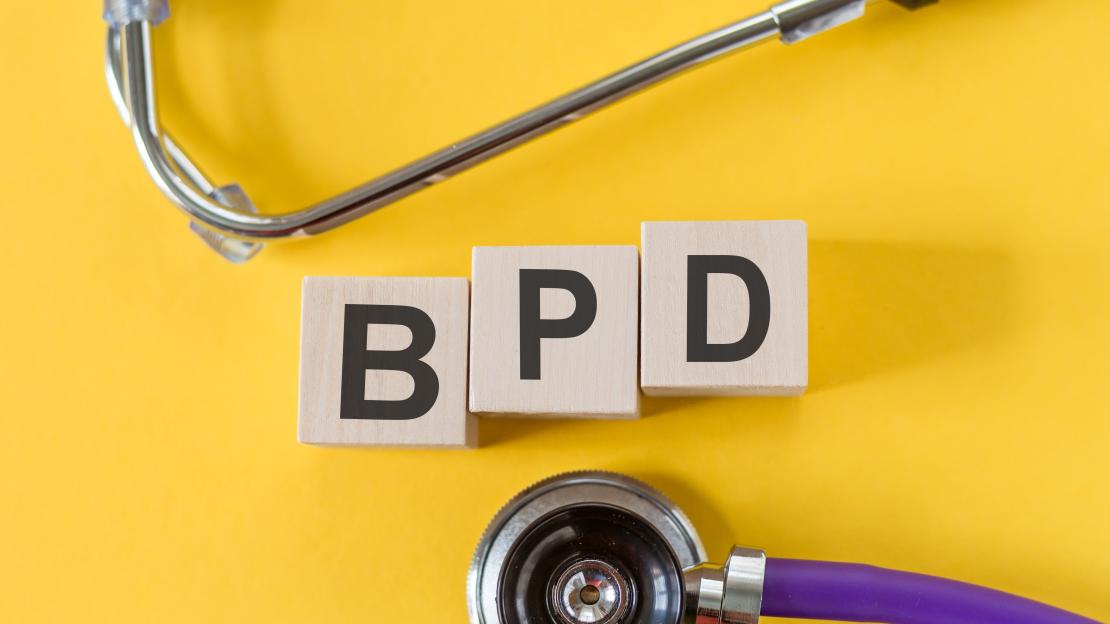 A photo of blocks reading BPD surrounded by a stethoscope on a yellow background.