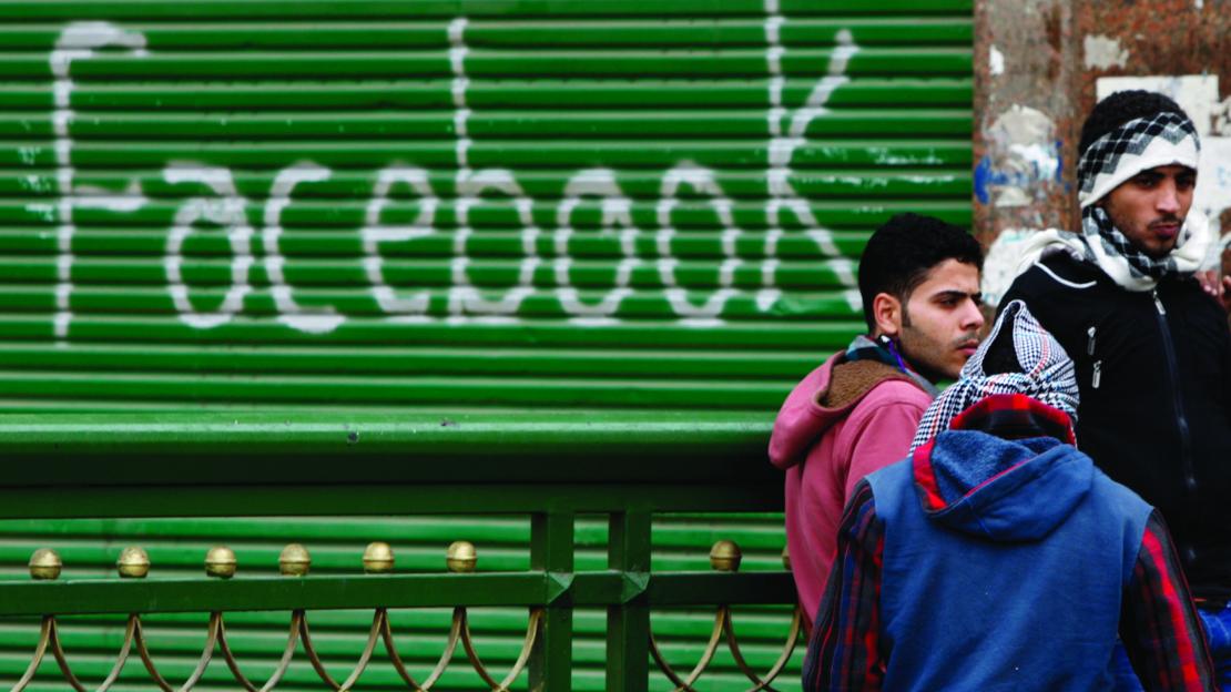 Protesters at Tahrir Square in Egypt stand near graffiti celebrating Facebook.