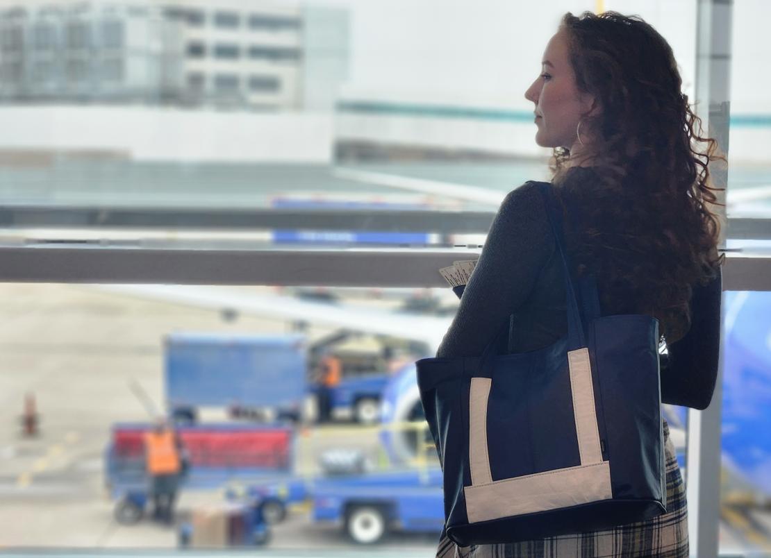 Lynne Corvaglia with a blue and white leather bag at an airport.