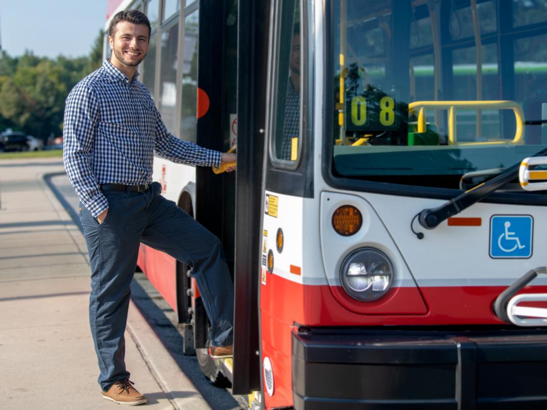 Bobby Hristova stands beside a TTC bus.