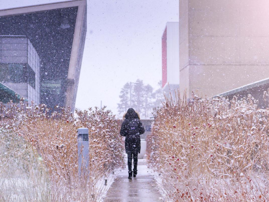 Photo of person walking through a snowy UTSC campus.
