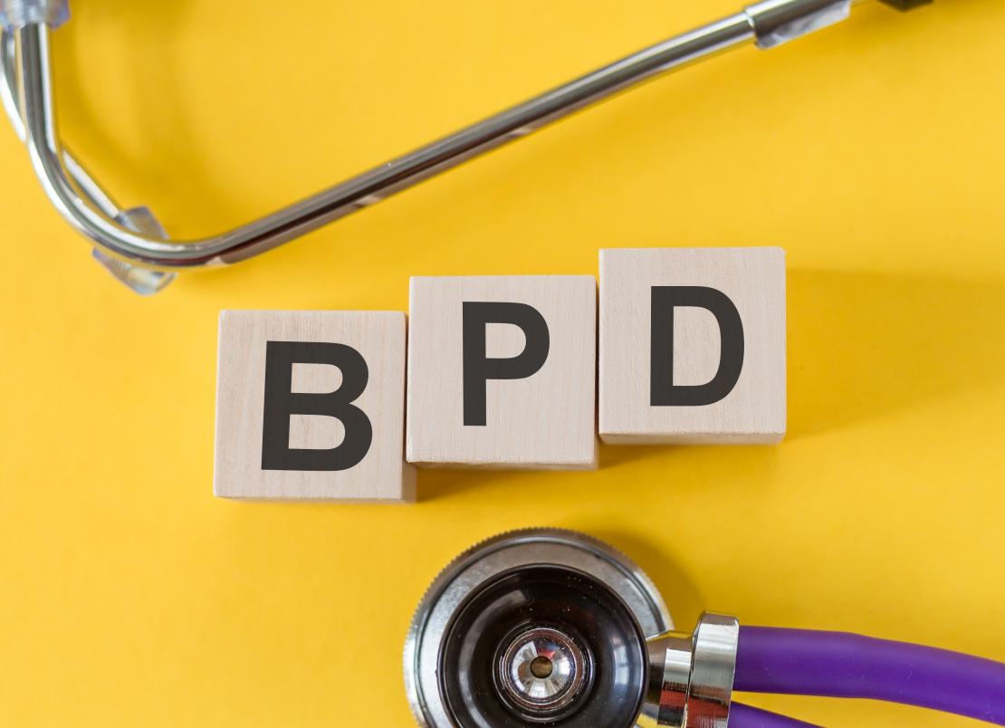 A photo of blocks reading BPD surrounded by a stethoscope on a yellow background.