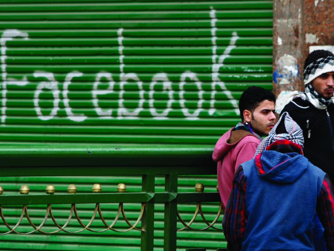 Protesters at Tahrir Square in Egypt stand near graffiti celebrating Facebook.