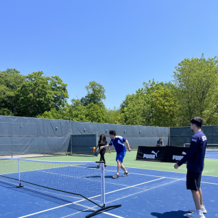 Three people playing pickleball on a court