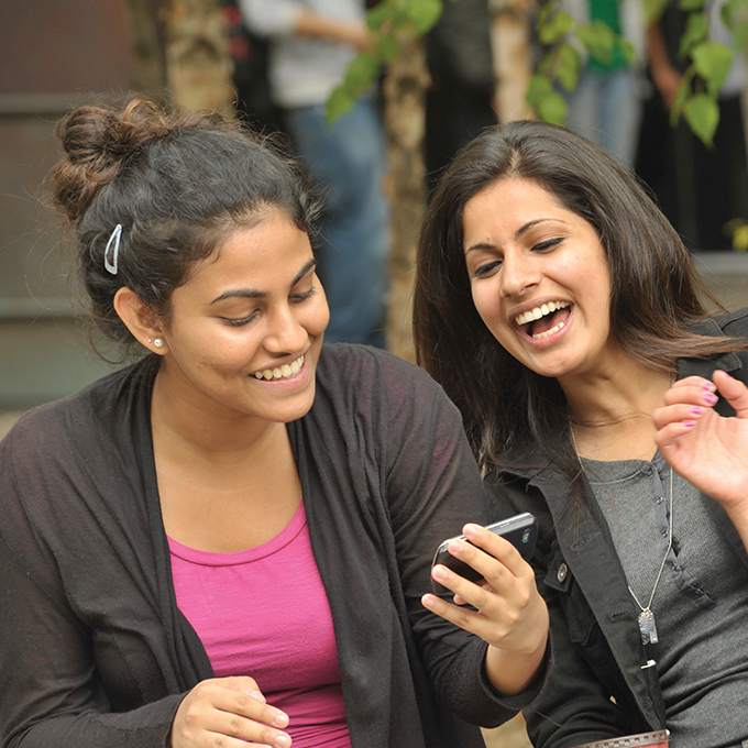 Two UTSC students looking at a phone and laughing