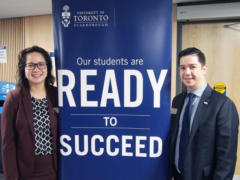 Joanna Ying and Michael Tacorda standing in front of a banner that reads "our students are ready to succeed"