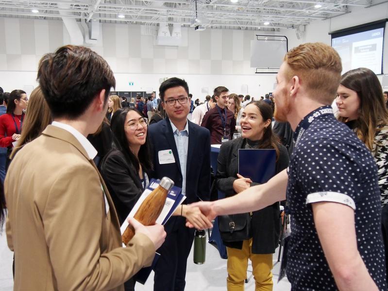 Students shaking hands with an employer at networking event
