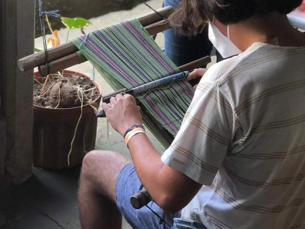 person weaving on a traditional weaving tool
